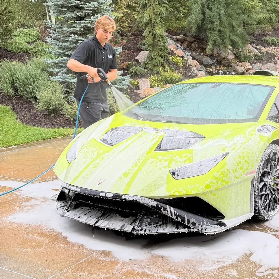 Signature crew member foam-washing a lime green Lamborghini Huracán